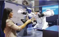  ?? (Photo by Chen Shangwen/People’s Daily) ?? A staff member of German company SCHUNK interacts with a robotic arm at the equipment section.