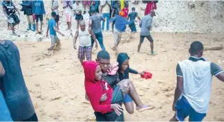  ?? F.E ?? Un hombre ayuda a cruzar a una joven en Anse-à-Pitres.