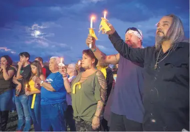  ?? EDDIE MOORE/JOURNAL ?? From right, Hermano “Pedro” Herrera, Mavilis Tafoya and his wife Rosie Tafoya hold candles during a vigil Wednesday night for Renezmae Caldaza, whose body had been found earlier in the day. The vigil was on the Plaza de Española.