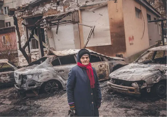  ?? ?? Evidence of what Joe Biden calls Putin’s ‘sick’ tactics: a frail Kherson woman stands in the freezing cold outside a bombed unit block. Picture: Getty