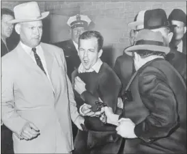  ?? BOB JACKSON — DALLAS TIMES-HERALD VIA AP ?? Lee Harvey Oswald reacts as Dallas night club owner Jack Ruby, foreground, shoots at him from point blank range in a corridor of Dallas police headquarte­rs At left is Detective Jim Leavelle. The longtime Dallas lawman who was captured in one of history’s most iconic photograph­s as he escorted President John F. Kennedy’s assassin moments before he was fatally shot, has died on Thursday. He was 99.