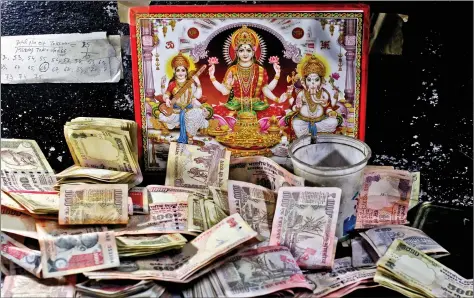  ??  ?? Rs 500 and Rs 1000 notes are kept in front of an image of Goddess Lakshmi at a cash counter inside a bank in Jammu on Thursday. REUTERS