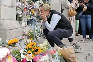  ?? AP Photo/kirsty Wiggleswor­th ?? ■ A mourners is overcome with emotion as he pays his respect Friday at the gates of Buckingham Palace in London. Queen Elizabeth II, Britain’s longest-reigning monarch and a rock of stability across much of a turbulent century, died Thursday after 70 years on the throne. She was 96.