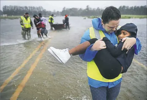  ?? Chip Somodevill­a/Getty Images ?? Volunteer Amber Hersel from the Civilian Crisis Response Team helps rescue 7-year-old Keiyana Cromartie and her family from their flooded home Friday in James City, N.C.