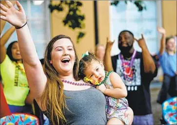  ?? HAYLEY BOSARGE Gerald Herbert Associated Press ?? and her daughter Ellie, 2, attend a Mardi Gras-style parade that drew thousands of revelers, many without masks, Friday in Mobile, Ala. The state’s vaccinatio­n rate is one of the nation’s lowest.