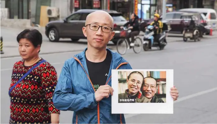  ?? FOTO: JORGEN LOHNE ?? Aktivisten Hu Jia viser frem portrettet av sine venner, den nå avdøde nobelprisv­inner Liu Xiaobo og hans kone Liu Xia.