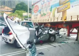  ?? BERNAMAPIX ?? ... The mangled car after it hit the trailer at a junction at Km121 of the Johor Baru-Malacca road yesterday. The car driver and his passenger were killed in the accident.