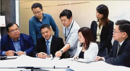  ??  ?? Working together: (seated from left) Tay, Yang and Low (right) having a discussion with the team on how to take the
company forward.