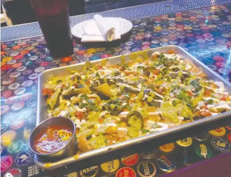  ?? PHOTO BY JIM TANNER ?? Smoked chicken chili nachos ($12) starts with a pan of pulled smoked-chicken chili over chips, topped with spicy avocado cream, pico de gallo, chile verde salsa, sour cream, jalapeno and pepper jack cheese.