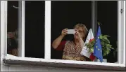  ?? AP ?? A Polish woman shows her support decorating the window of the apartment with a European Union flag during a street protest in Warsaw, Poland.