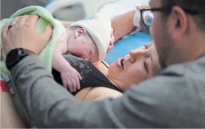  ?? JONATHAN HAYWARD THE CANADIAN PRESS ?? Kate Chong holds her new baby girl Adelynn Susandrea Chong right after delivery as husband Brian looks on at St. Paul's hospital in downtown Vancouver June 14.