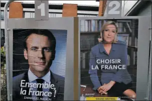  ?? The Associated Press ?? FRENCH VOTE: Election campaign posters for French centrist presidenti­al candidate Emmanuel Macron and far-right candidate Marine Le Pen are displayed in front of the polling station where Marine Le Pen will vote in Henin Beaumont, northern France....
