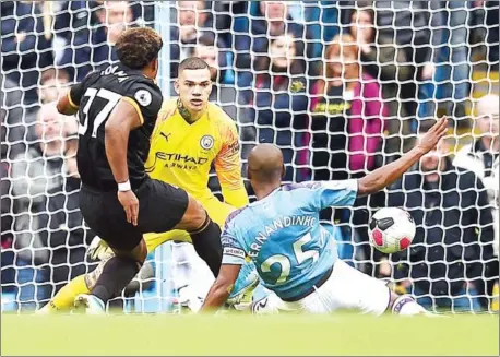  ?? OLI SCARFF/AFP ?? Wolverhamp­ton Wanderers striker Adama Traore (left) scores his team’s second goal past Manchester City goalkeeper Ederson during the English Premier League football match at the Etihad Stadium in Manchester, north west England, on Sunday.