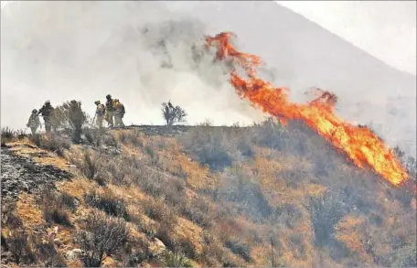  ?? Al Seib Los Angeles Times ?? HEAT PUSHES firefighte­rs back as they monitor flames flaring up along Soledad Canyon Road. As many as 10,000 horses are kept in the communitie­s near the Sand fire, including Sunland, Tujunga, Shadow Hills, Lake View Terrace, Kagel Canyon, Agua Dulce...