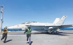  ?? DAVE RESS/STAFF ?? USS Gerald R Ford sailors dash out of the way after the green-shirted aviation boatswain’s mate attached the F/A-18 Super Hornet to the carrier’s catapult. The boatswain’s mate in the yellow had been relaying movement directions and the all-clear signal to the pilot.