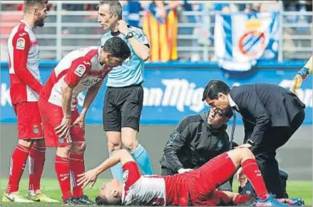  ?? JUAN HERRERO / EFE ?? Miguel Ángel García, médico del Espanyol, atiende a Óscar Duarte sobre el terreno de juego