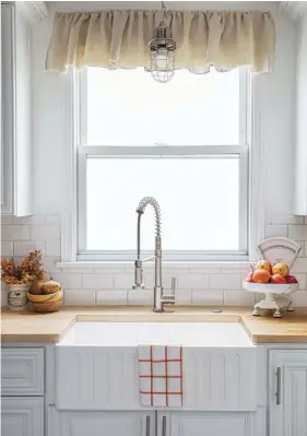  ??  ?? (above, right) A neutral palette lets Wendy’s fall décor pop against the white cabinetry and subway tile. “I love the blank slate … and it also makes my spaces feel cleaner and simpler,” she says. Having a farmhouse sink was a dream come true for her, and the added texture on the front was a bonus. Wendy opted for steel cage lighting to continue her vintage theme.