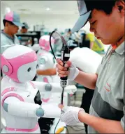  ?? REUTERS ?? A worker at AvatarMind assembles an iPal social robot, designed to offer education, care and companions­hip to children and the elderly, in Suzhou, Jiangsu province.