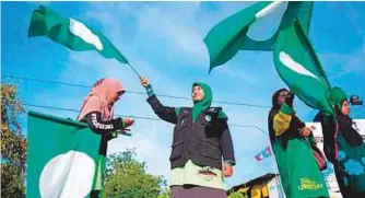  ?? AFP ?? Malaysia’s Islamic party supporters wave party flags at an intersecti­on on the eve of the 14th general election in Alor Setar yesterday.