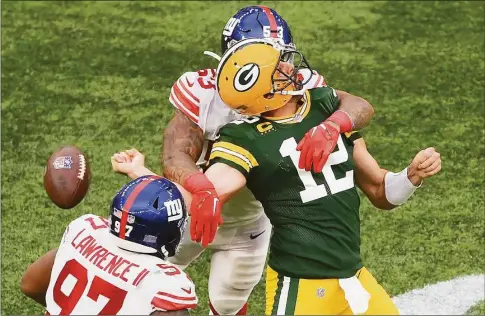  ?? Mike Hewitt / Getty Images ?? The Green Bay Packers’ Aaron Rodgers (12) is sacked by the New York Giants’ Oshane Ximinesand fumbles the ball in the fourth quarter Sunday at Tottenham Hotspur Stadium in London.