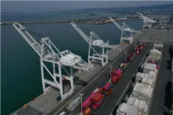  ?? GETTY IMAGES ?? FEELING THE EFFECTS: Cranes sit idle Friday at the Port of Oakland, Calif., where shipping traffic is down 20% becaue of the coronaviru­s. In Boston, at right, a pedestrian passes a crawler detailing stock market losses Friday. And in Seoul, South Korea, below, cleaners disinfect a subway station.