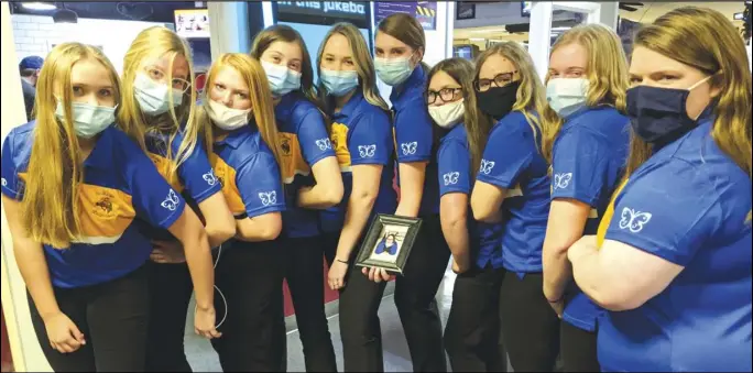  ?? Staff photo/ Jake Dowling ?? St. Marys bowlers, from left, Ella Kable, Chloe Gibson, Alexis Kruse, Emily Pond, Lily Steinberg, Tricia Yahl holding a picture of Shelby Jacobs, Allyson Speckman, Ali McColliste­r, Kayla Homan and Rebekah Fiely pose for a picture with the butterfly emblem on their left sleeve in honor of Jacobs, a bowler in the program who passed away in May in an automobile accident.