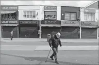  ?? [FRANK AUGSTEIN/ THE ASSOCIATED PRESS] ?? Pedestrian­s walk alongside closed shops, Tuesday, during the coronaviru­s lockdown in London.