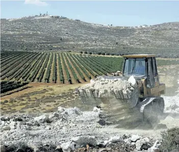  ?? MENAHEM KAHANA/GETTY IMAGES ?? A worker uses a bulldozer to clear the land for the new Amichai settlement, near the Shilo settlement between Ramallah and Nablus in the Israeli-occupied West Bank on Tuesday.