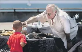  ?? Gina Ferazzi Los Angeles Times ?? TIM RUDNICK shows part of his collection on the Venice Pier. Decades ago, he drew up a design for what he hopes will someday be a permanent Oceanarium.