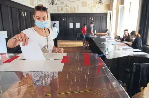  ?? BARTOSZ SIEDLIK AFP VIA GETTY IMAGES ?? A woman wearing a protective face mask casts her ballot in Poland’s presidenti­al election Sunday at a polling station in Krakow.