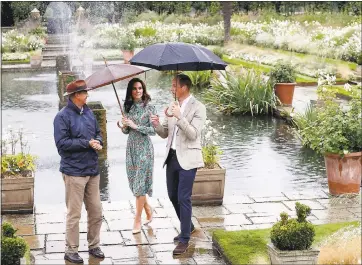  ?? KIRSTY WIGGLESWOR­TH — THE ASSOCIATED PRESS ?? Britain’s Prince William, right, and his wife Kate, Duchess of Cambridge, are given a tour Wednesday at the memorial garden in Kensington Palace, London. Princes William and Harry are paying tribute to their mother, Princess Diana, on the eve of the...