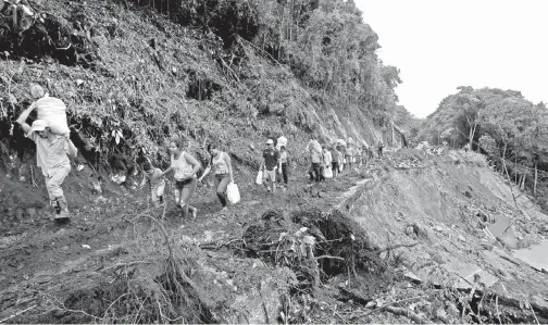  ??  ?? PENUMPANG bas yang terkandas akibat tanah runtuh melalui sebatang jalan raya yang terjejas teruk akibat kemaraan Nate di Casa Mata, Costa Rica kelmarin. — Gambar Reuters