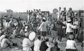  ??  ?? 1955年，一师胜利农业生产社的­社员们，参观某农场拖拉机耕作，并与战士们联欢。