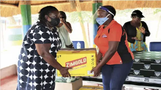  ??  ?? Maám Danai Simbi, SECURICO Admin Director, handing over food stuffs to Mrs Olinah Mabhiza from Chiedza Child Care Centre, Waterfalls, Harare