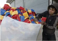  ?? (Mahmoud Hassano/Reuters) ?? MOHAMMED ABU RDAN puts dishcloths in a bag in front of the factory he works at in the Turkish-occupied region of northern Syria last week.