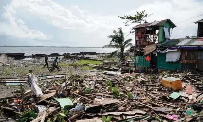  ?? Photograph: Bobbie Alota/AFP via Getty Images ?? Residents walk past a house damaged during Typhoon Phanfone in Tacloban.