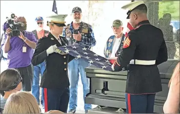  ??  ?? Two U.S. Marines fold the flag that had been draped over veteran Richard Lindsay Butterfiel­d’s casket during his funeral service Wednesday at Georgia National Cemetery.