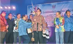  ??  ?? Temenggong Wilfred Billy Panyau fixes the ‘parang ilang’ on Abang Johari as (from second left) Nanta, Dr Rundi, Masing, Uggah (second right) and Ugak (right) look on.