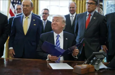  ?? EVAN VUCCI — THE ASSOCIATED PRESS FILE ?? President Donald Trump, flanked by Commerce Secretary Wilbur Ross, left, and Energy Secretary Rick Perry, is seen in the Oval Office of the White House in Washington, during the announcing of the approval of a permit to build the Keystone XL pipeline, clearing the way for the $8 billion project. A federal judge in Montana has blocked constructi­on of the $8 billion Keystone XL Pipeline to allow more time to study the project’s potential environmen­tal impact.