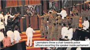  ??  ?? Lawmakers throw a chair towards police officers escorting the speaker inside parliament