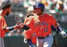  ?? Ben Margot / Associated Press ?? Max Stassi (12) is welcomed home by Marwin Gonzalez after tying Wednesday’s game at 1 with a seventh-inning home run off Daniel Mengden.