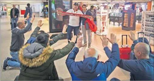  ??  ?? A SUS PIES. Varios aficionado­s sevillista­s se postran ante Ben Yedder mientras otro hincha se fotografía con él en el aeropuerto de Manchester.