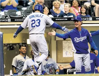  ?? Tom Lynn / Getty Images ?? Adrian Gonzalez is greeted by manager Don Mattingly and a bunch of bubbles after a homer.