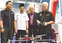  ??  ?? Idris (right) test-flies a drone at an exhibition booth during the National Higher Education Carnival in Malacca yesterday.