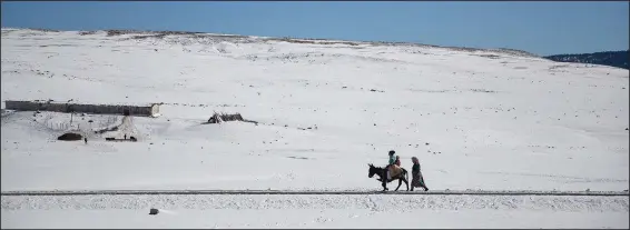  ?? (AP/Mosa’ab Elshamy) ?? A family crosses a road Dec. 4 amidst the snow to collect water in the Amazigh Timahdite village in the Middle Atlas, near Azrou, Morocco.