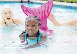  ?? JENNIFER LETT/STAFF PHOTOGRAPH­ER ?? Naomi Hied, 8, who suffers from sickle cell anemia, wriggled into her own custom-fitted fins to swim laps with two mermaids at the Boca Beach Club.