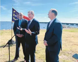  ?? KARI PUGH/STAFF ?? Gov. Roy Cooper, center, flanked by Federal Highway Administra­tor Shalien Bhat, left, and North Carolina Transporta­tion Secretary J. Eric Boyette, celebrate a $110 million grant to replace the aging Alligator River bridge in northeaste­rn North Carolina.