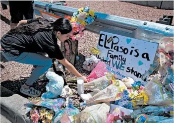  ?? MARK RALSTON/GETTY-AFP ?? A woman on Sunday places flowers at a memorial outside an El Paso Walmart, where 20 people were killed Saturday.