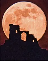  ??  ?? Night vision: Pink Super Moon rises behind Mow Cop Castle in Cheshire