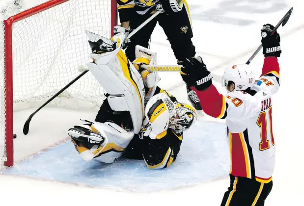  ?? — THE ASSOCIATED PRESS ?? Penguins goalie Matt Murray takes a tumble as Calgary’s Derek Ryan celebrates the game’s first goal by teammate Andrew Mangiapane. The Flames’ first line was held in check but secondary scorers came up big in a 5-4 win.